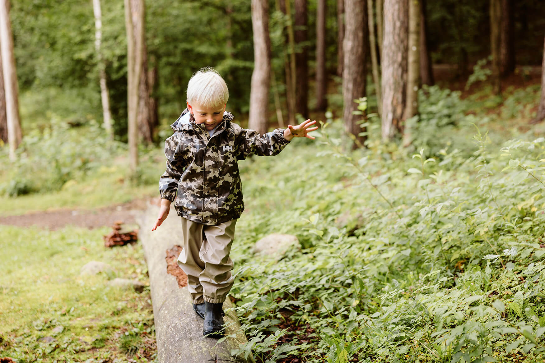 boy balancing on a log in the forest