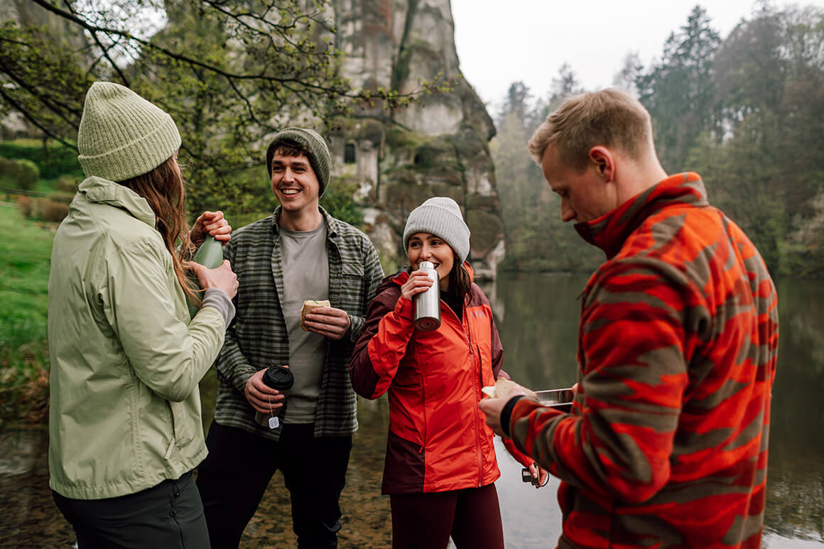 four people standing in the forest by a lake