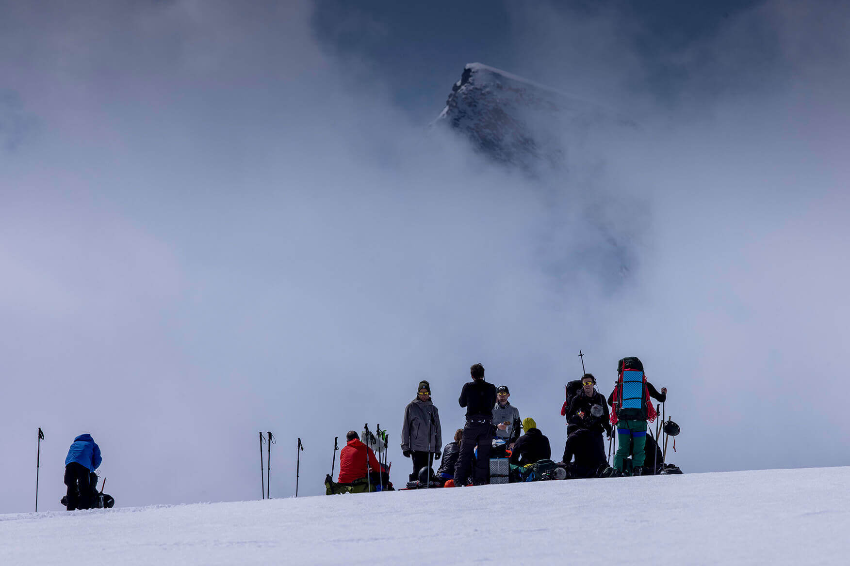 a group of people standing on a glacier with a mountain in the background