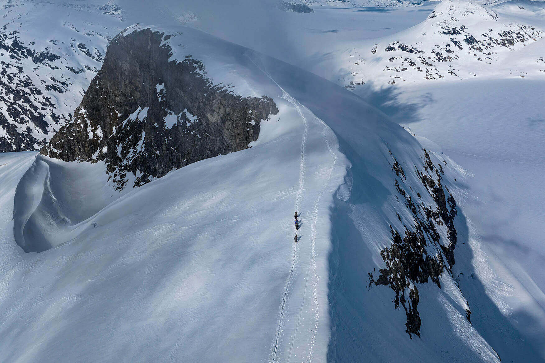 people walking down the top of a mountain in snow