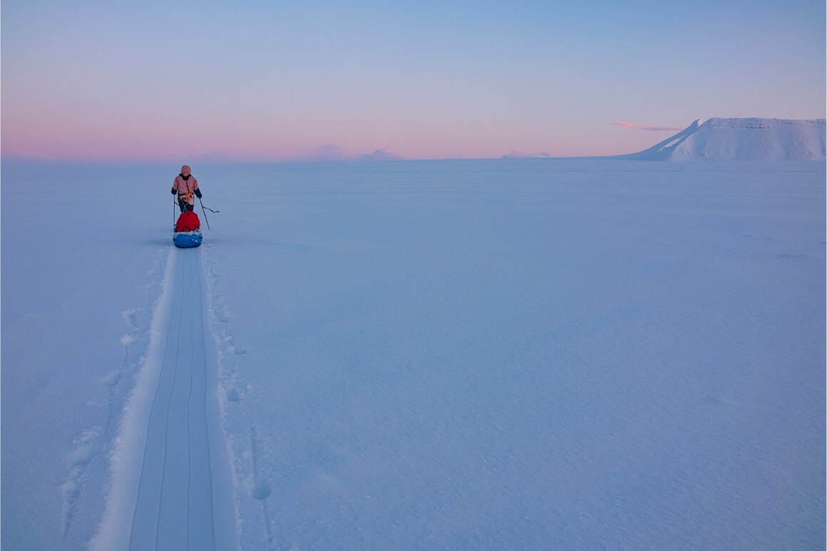 caroline cote pulling sled on snow at sunset