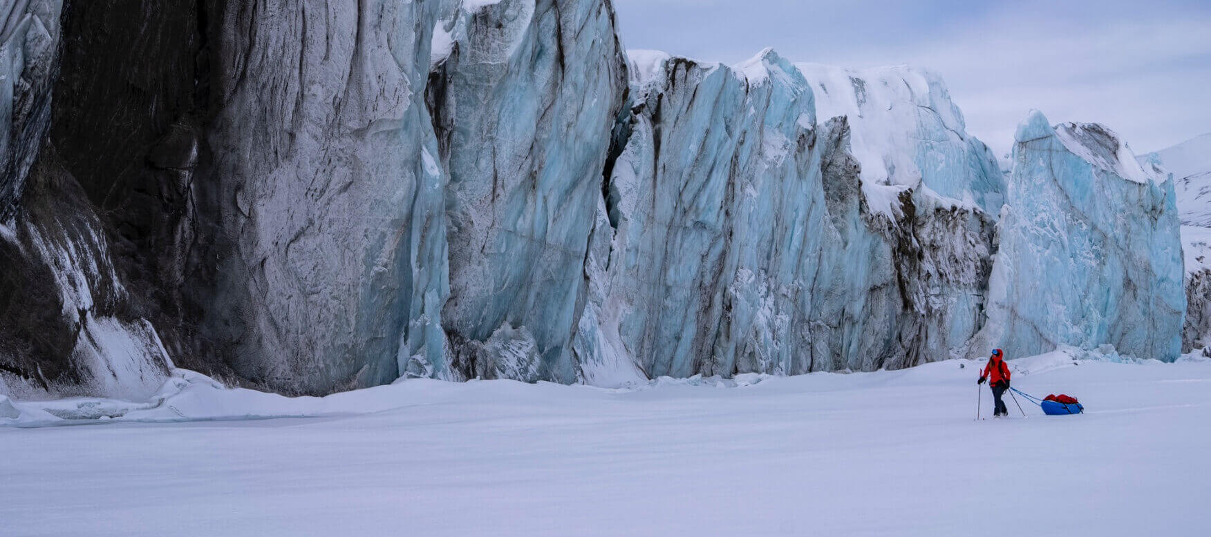 caroline cote pulling sled by large ice wall