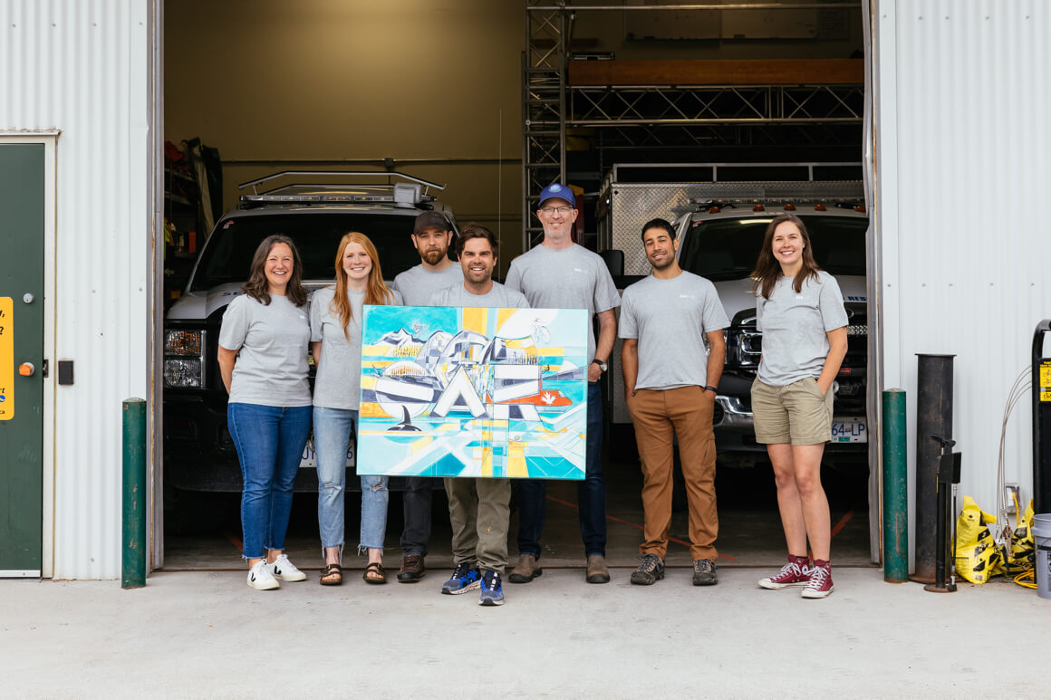 group of people posing with a painting 