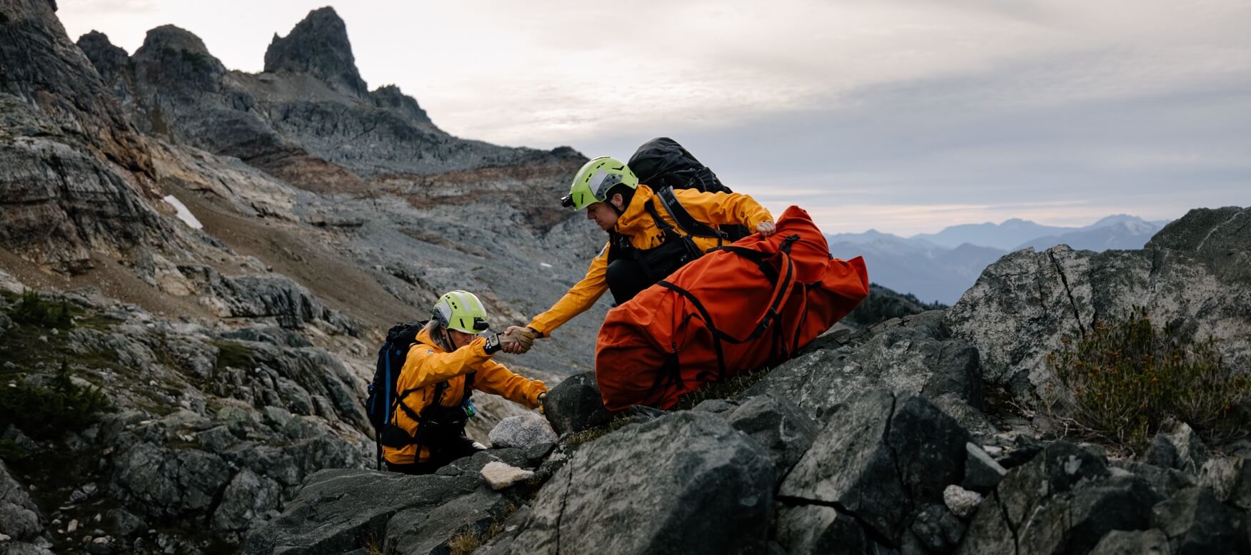 2 people helping each other up the mountain to rescue someone