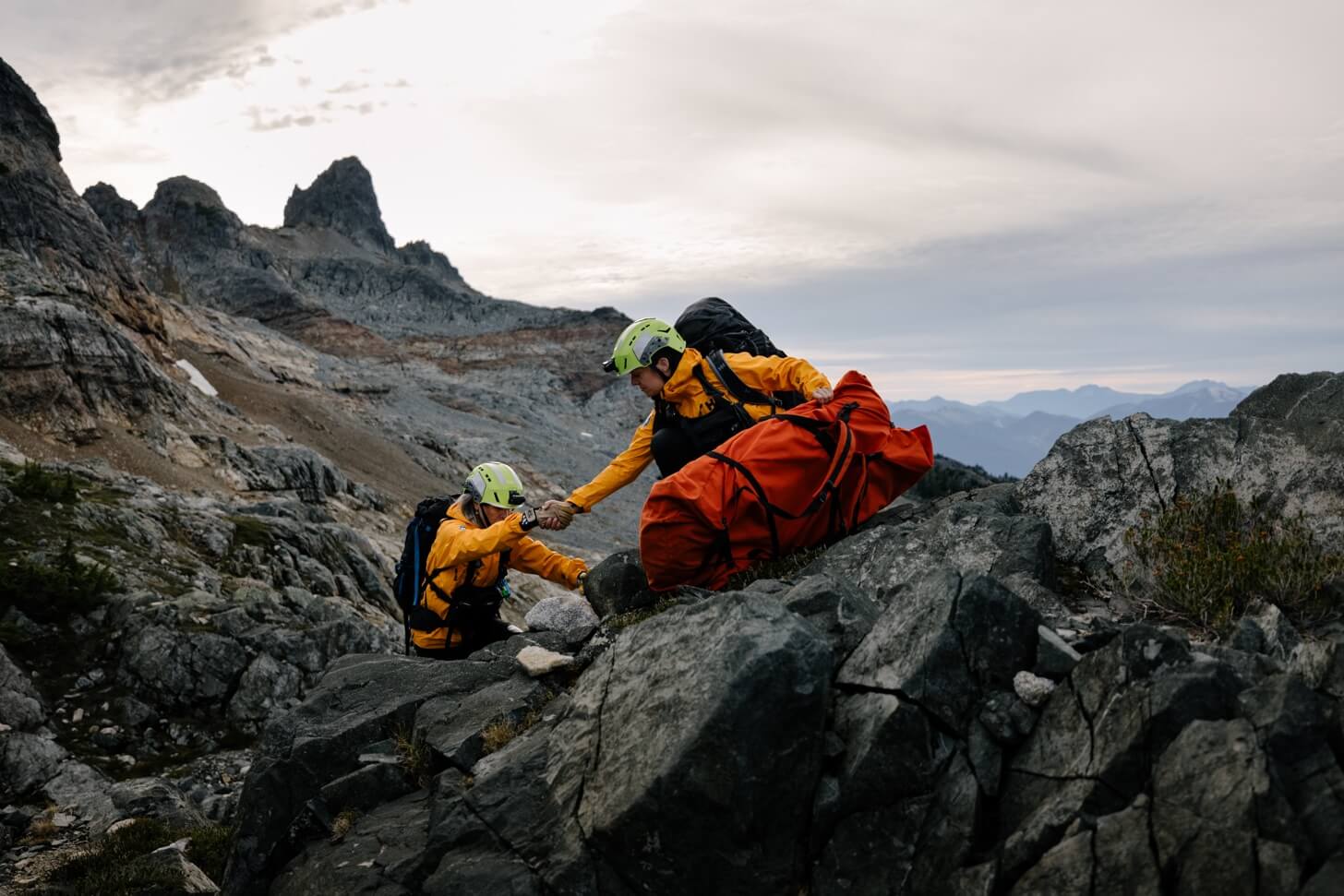 2 people helping each other up the mountain to rescue someone