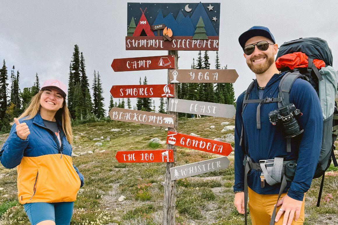 Andy and Anna standing next to the summit sleepover signs on the mountain