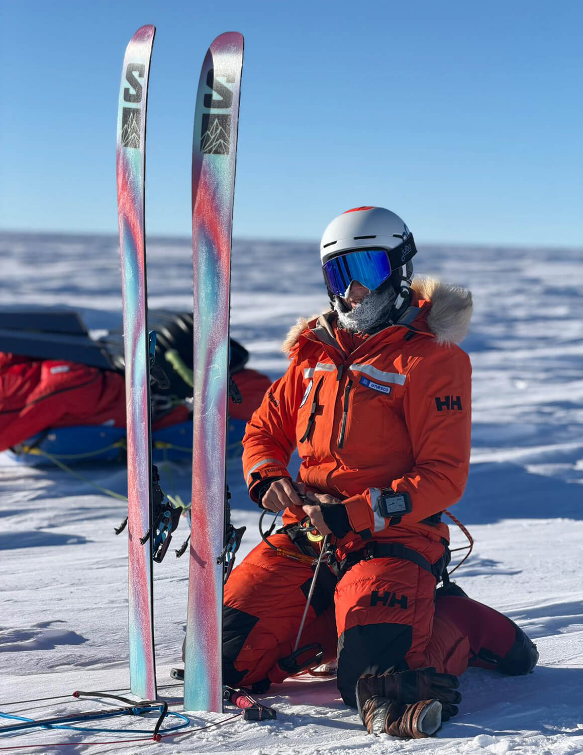 A woman kneeling in front of skis in Antarctica 