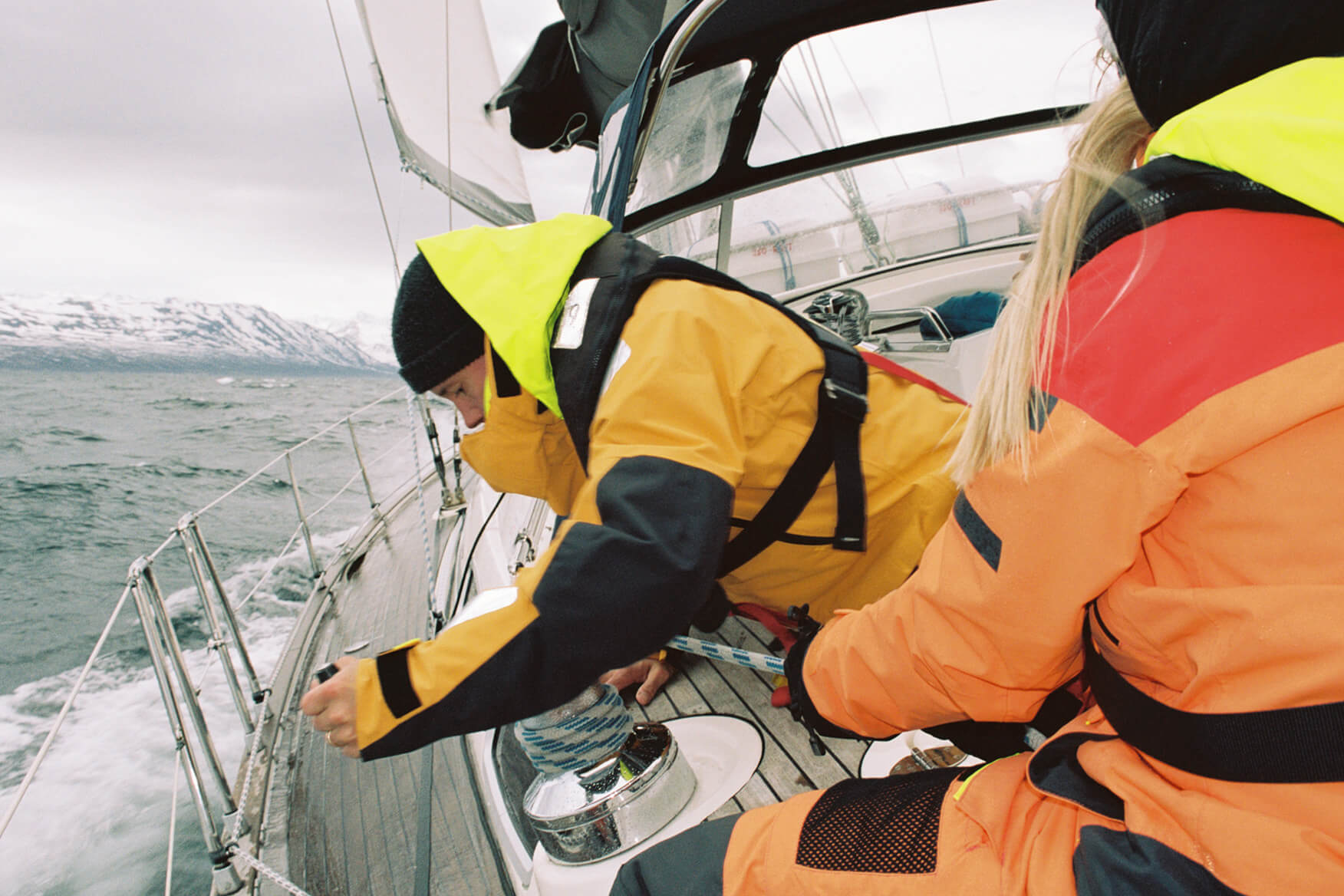 Learning the ropes, and beginning to realize what it means to tack for 12 hours straight. two sailors working the ropes on a sailing boat