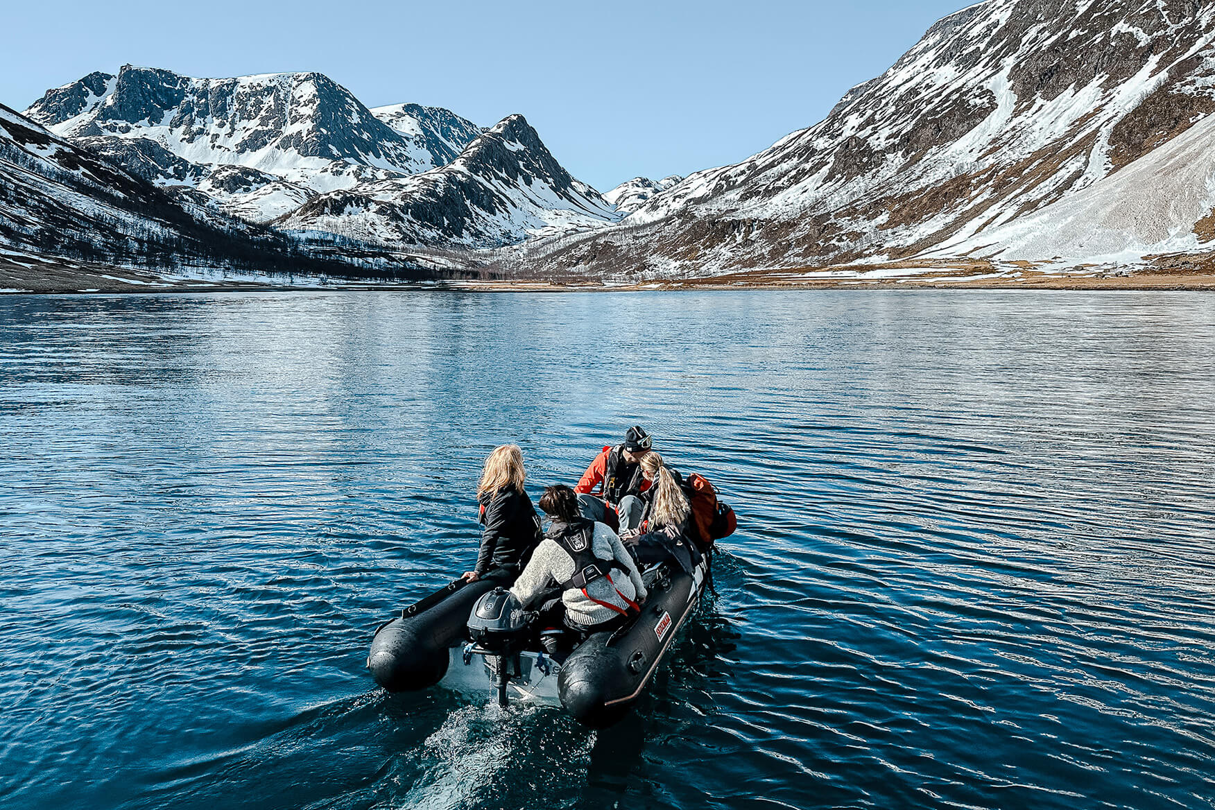After a night at anchor, skipper Helena brings the crew safely ashore for the first day of ski touring. dinghy with four people in a fjord in Finnmark