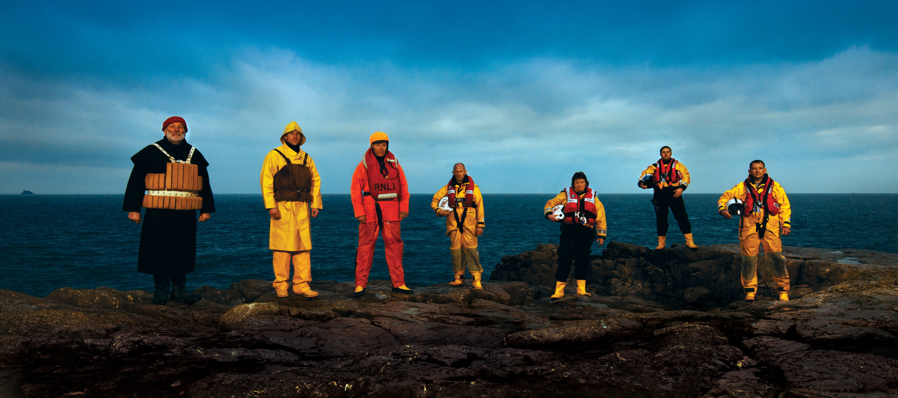 group of rnli members on rocks in front of the ocean