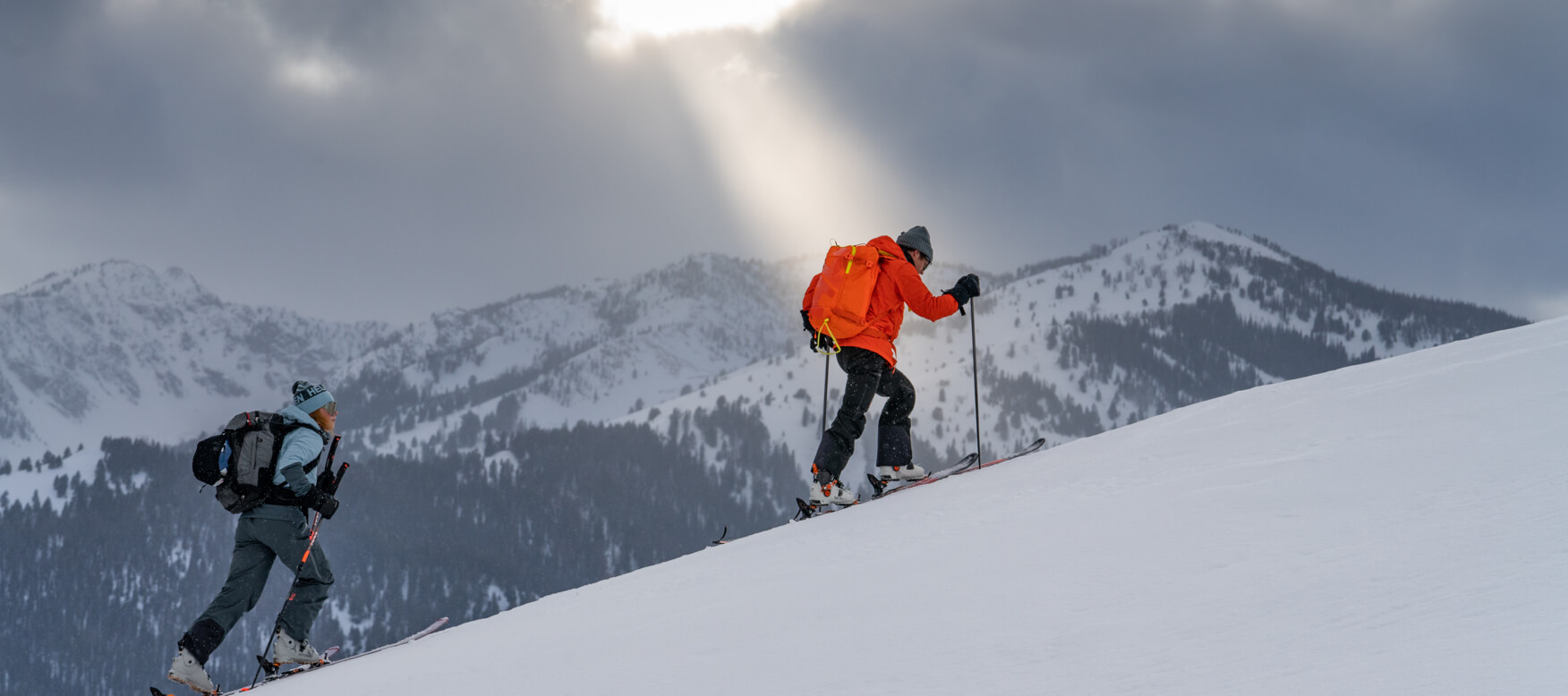 2 men hiking up the mountain with skis on 
