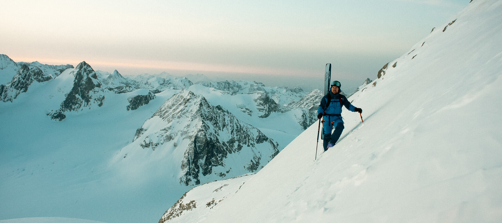 paul de groot hiking on a snowy mountain with skis on his back 