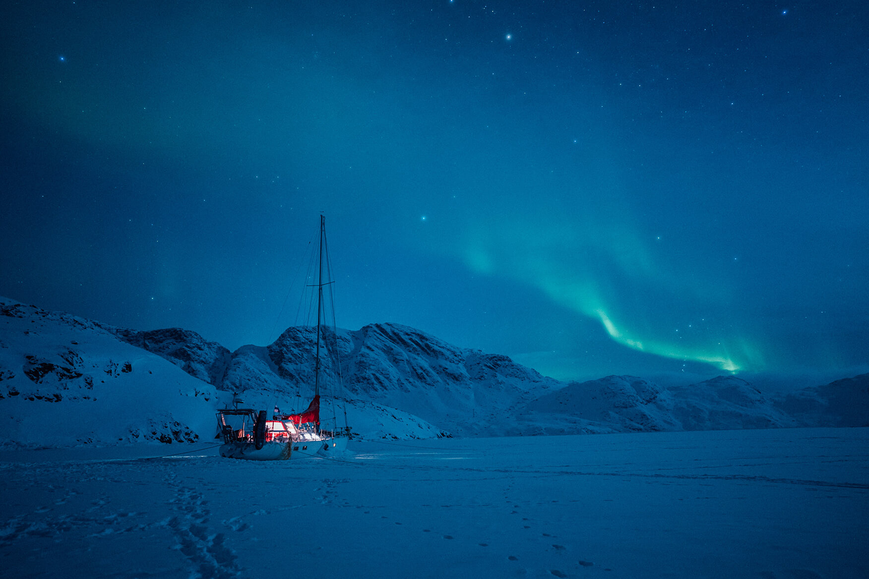 sailboat frozen in ice with northern light in the background