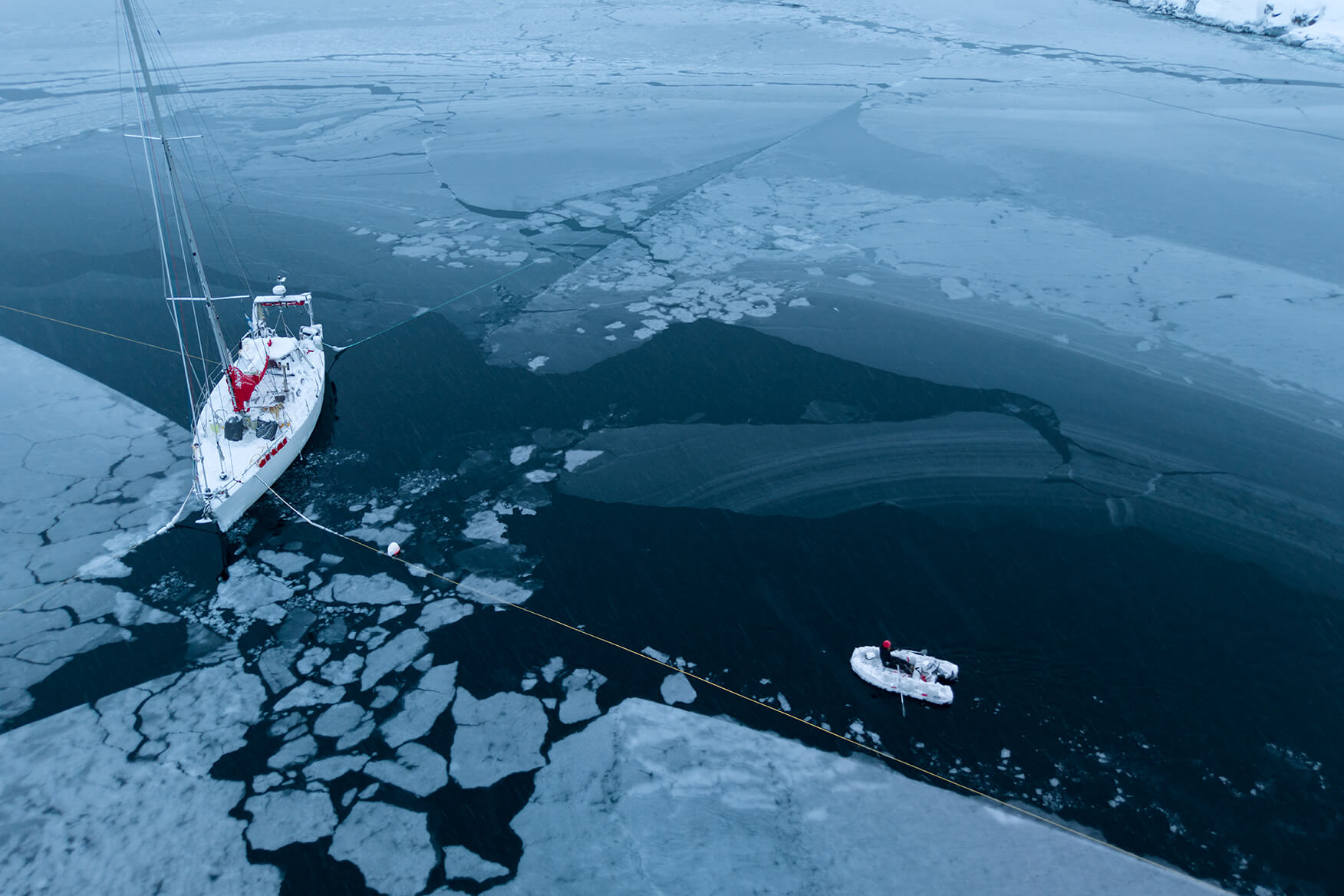 sailboat and a dinghy among arctic ice