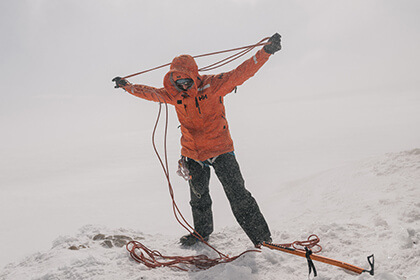 Man organizing a climbing rope in a blizzard