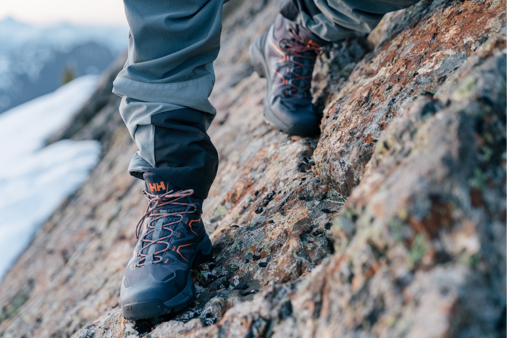 Close-up of hiking boots climbing down steep rockside.