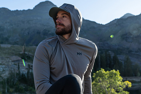 man sitting in nature wearing a hooded synthetic base layer