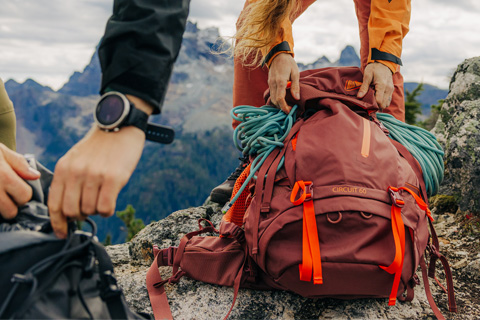 A woman hikes up a mountain carrying the Helly Hansen 45L Resistor Backpack Recco.