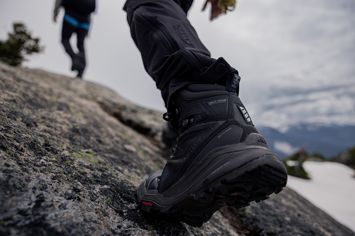 A person hiking up a rocky mountain in the black Helly Hansen Traverse HT boot.