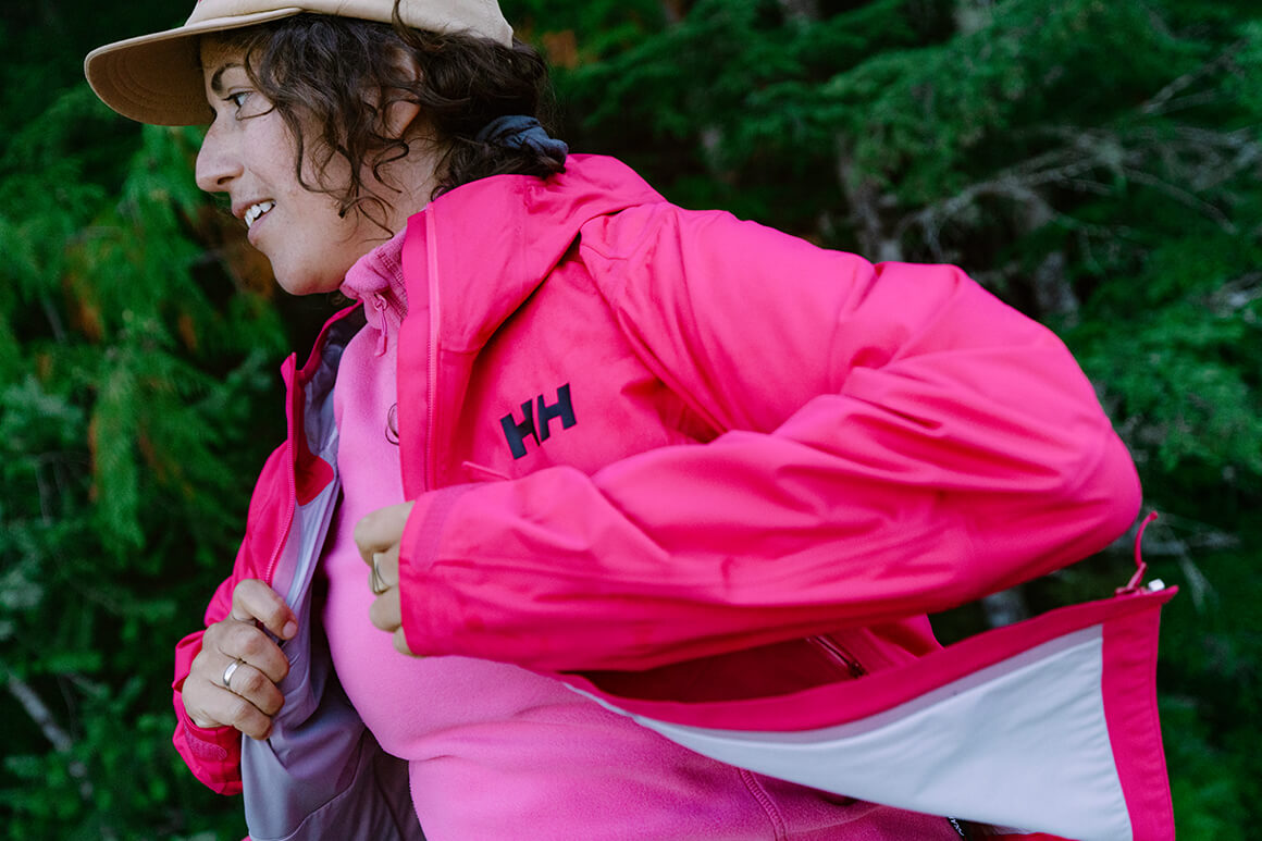 Woman putting on a pink hiking jacket