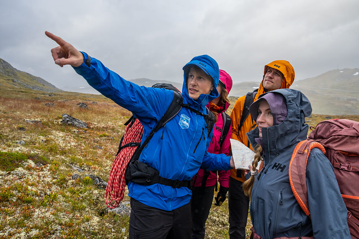 Mountain guide with three clients in the rain on a mountain plateau