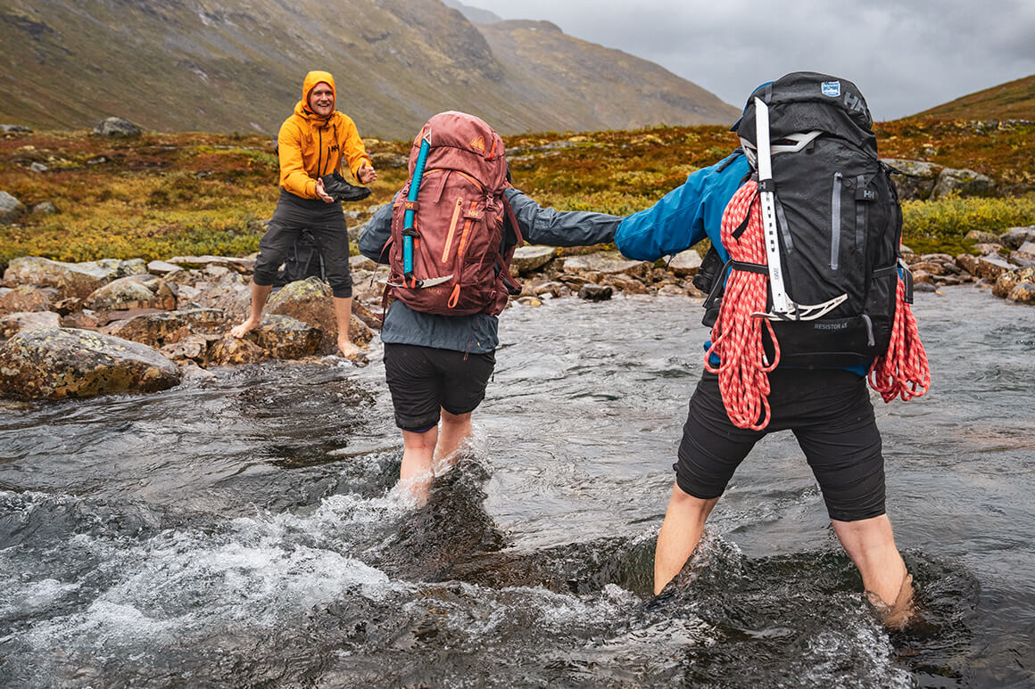 Man and woman crossing a river in the mountains