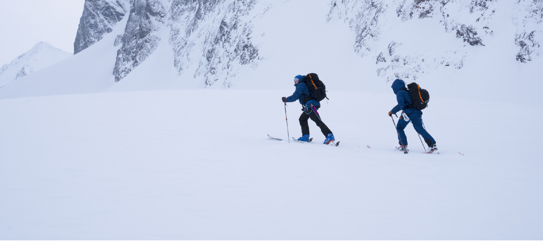 2 people hiking up a mountain on skiis