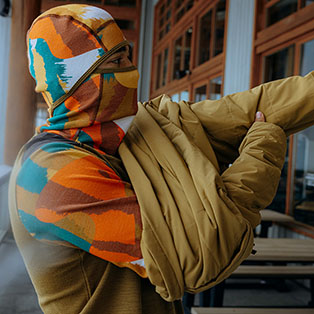 A man wearing a printed balaclava hoodie for skiing.