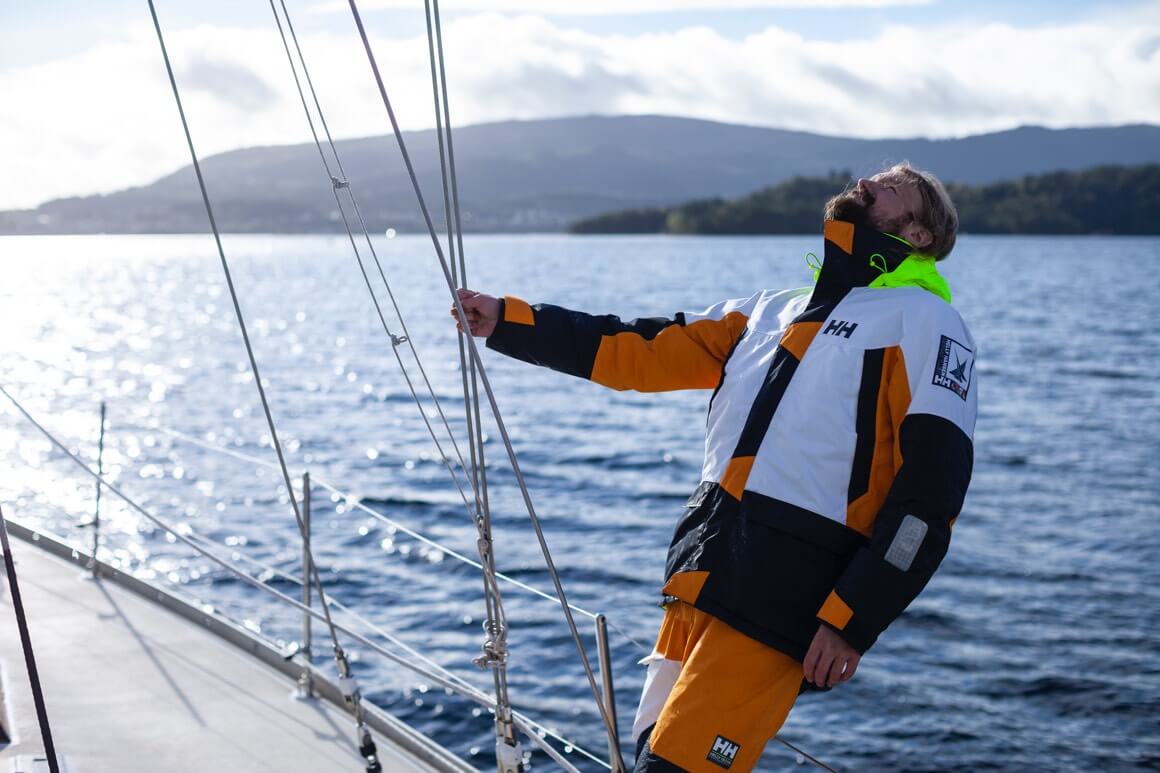 Man wearing the Newport Coastal Jacket looking up at sailing mast