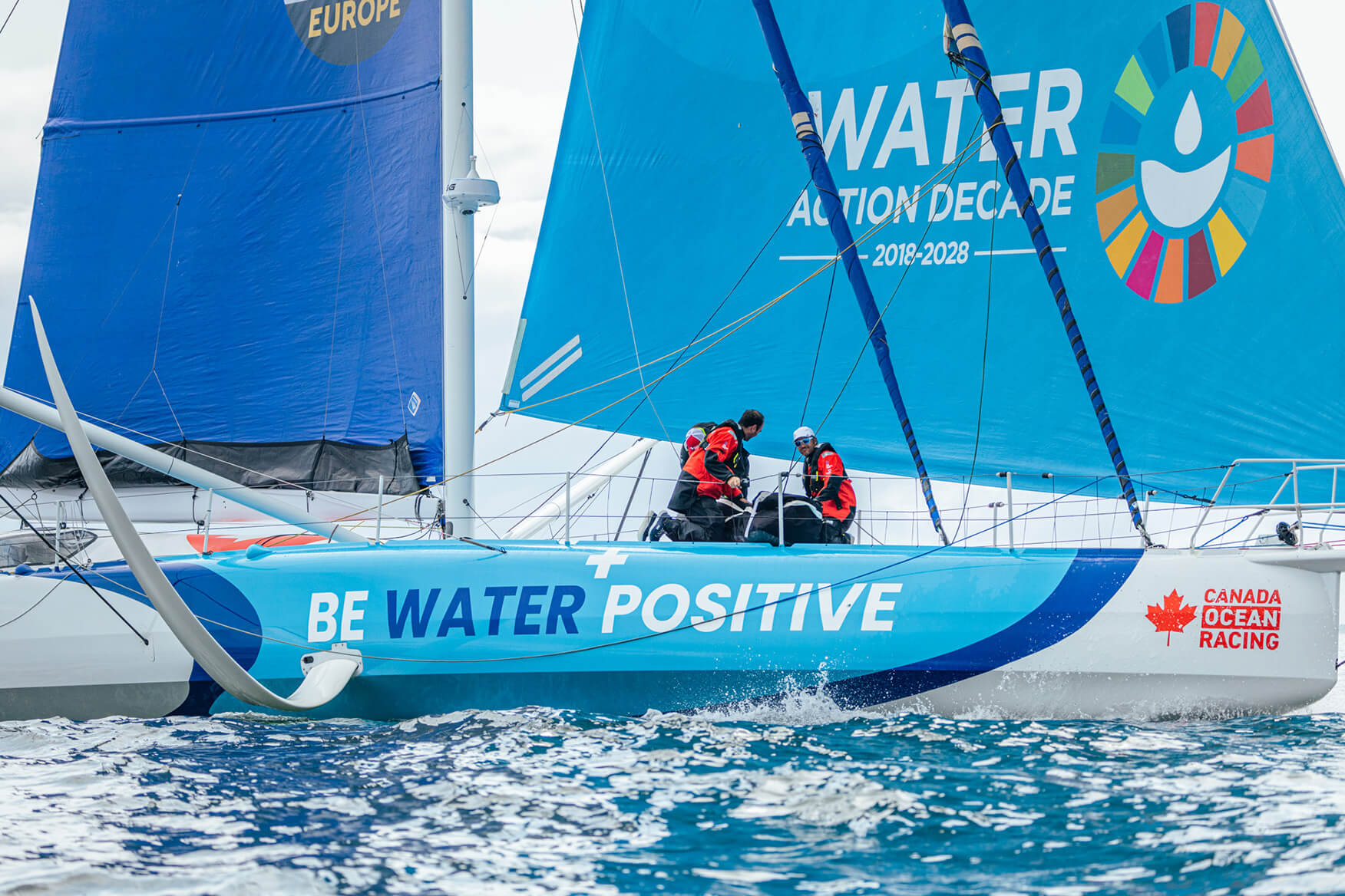 Two sailors on the deck of an IMOCA sailing boat