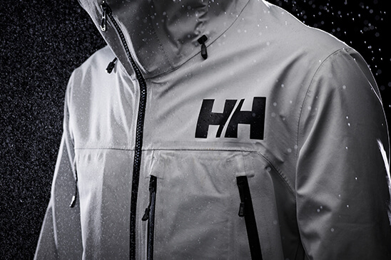 White jacket with HH logo on the chest, black background and raindrops falling down.